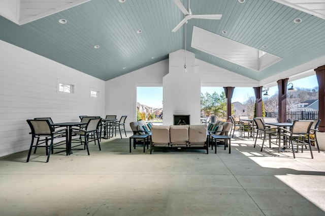 view of patio / terrace featuring ceiling fan and an outdoor living space with a fireplace