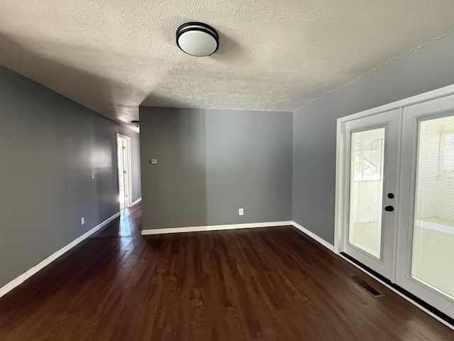 bonus room with dark wood-type flooring, a textured ceiling, and french doors