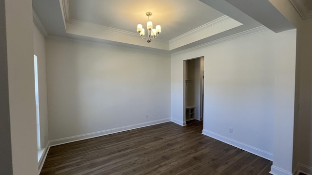 empty room with crown molding, dark hardwood / wood-style floors, a raised ceiling, and a chandelier