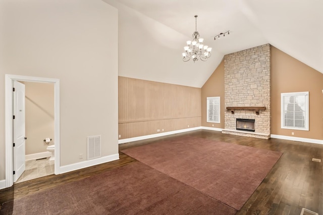 unfurnished living room with an inviting chandelier, a fireplace, high vaulted ceiling, and dark hardwood / wood-style floors