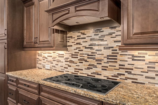 kitchen featuring premium range hood, tasteful backsplash, electric stovetop, and light stone counters