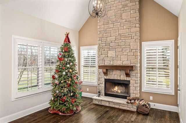 living room featuring dark wood-type flooring, a stone fireplace, high vaulted ceiling, and a notable chandelier