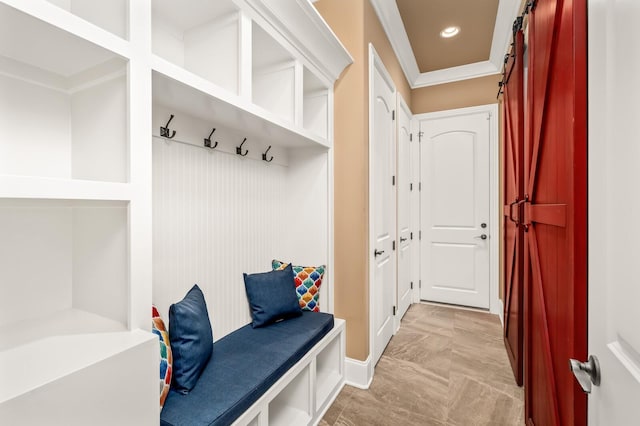 mudroom with crown molding and a barn door