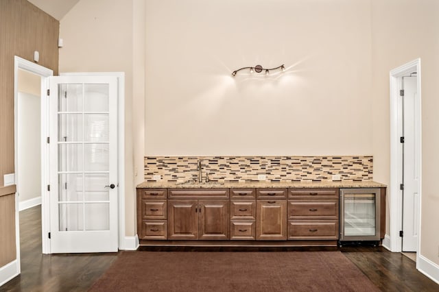 bathroom featuring wood-type flooring, sink, wine cooler, and backsplash