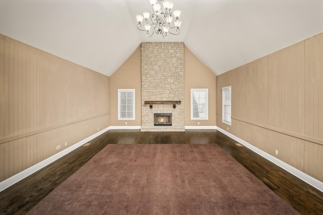 unfurnished living room with high vaulted ceiling, dark hardwood / wood-style floors, an inviting chandelier, and a fireplace