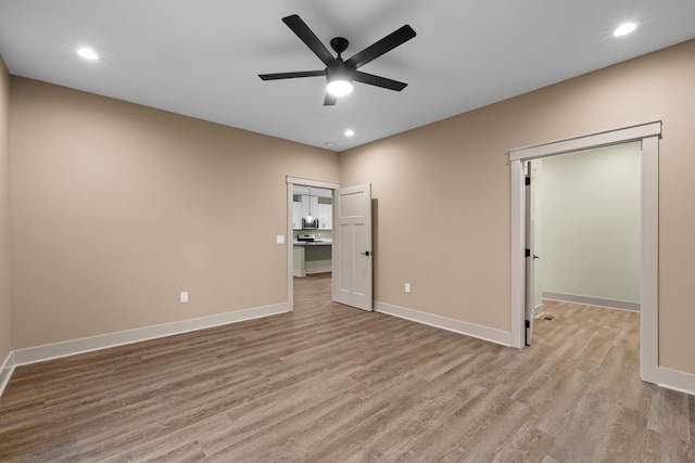 unfurnished bedroom featuring a walk in closet, light hardwood / wood-style flooring, and ceiling fan