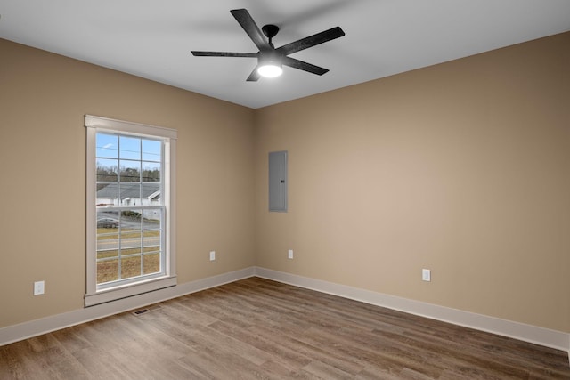 empty room featuring ceiling fan, electric panel, and hardwood / wood-style floors