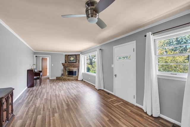 entryway with a brick fireplace, wood-type flooring, ornamental molding, and ceiling fan