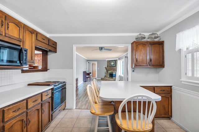 kitchen with crown molding, a breakfast bar area, range, a fireplace, and light tile patterned flooring