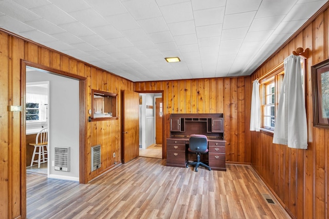 office with heating unit, light hardwood / wood-style floors, and wood walls