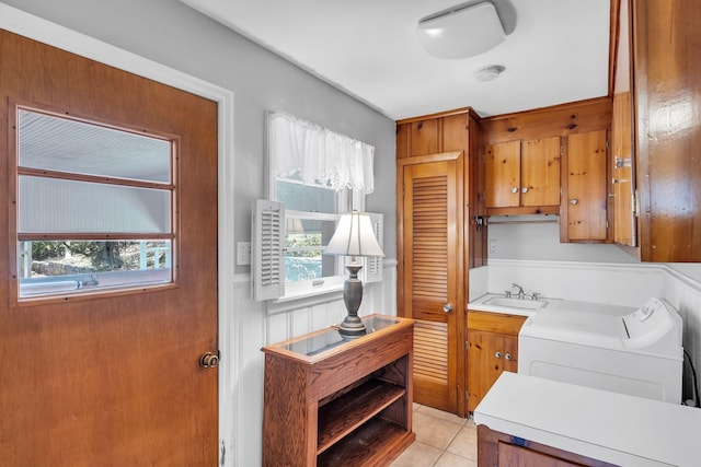 kitchen featuring sink, washing machine and clothes dryer, and light tile patterned flooring