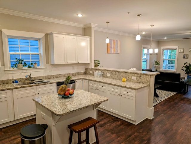 kitchen featuring a breakfast bar, sink, white cabinetry, hanging light fixtures, and dishwasher