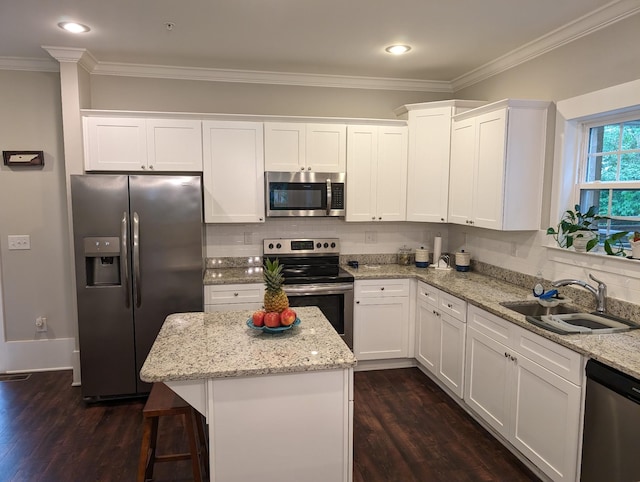 kitchen with a kitchen island, appliances with stainless steel finishes, sink, and white cabinets