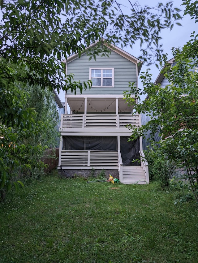 back of house featuring a balcony, a yard, and a sunroom