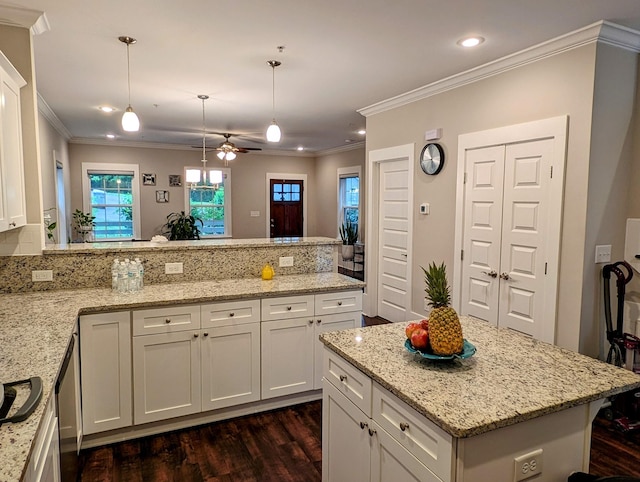 kitchen with hanging light fixtures, white cabinetry, and light stone countertops