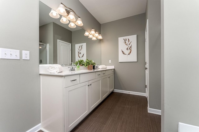 bathroom with a shower with door, vanity, and baseboards