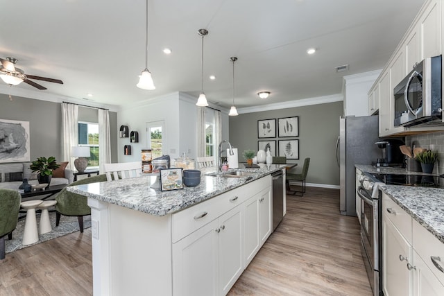 kitchen featuring white cabinetry, a center island with sink, appliances with stainless steel finishes, and pendant lighting