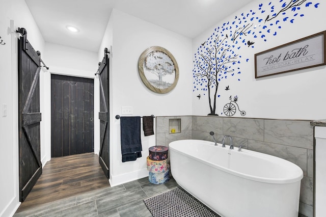 bathroom with a washtub, hardwood / wood-style floors, and tile walls