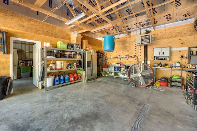 garage with stainless steel fridge with ice dispenser and a workshop area