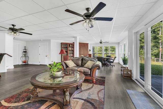 living room with dark hardwood / wood-style floors and a drop ceiling