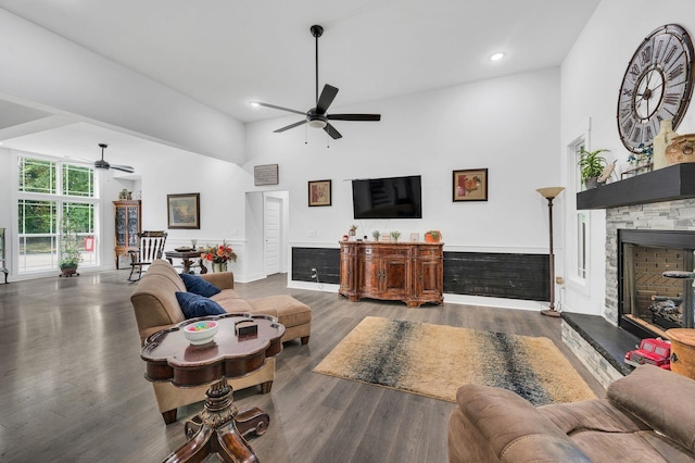 living room with a high ceiling, ceiling fan, dark wood-type flooring, and a fireplace