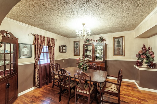 dining space featuring a notable chandelier, hardwood / wood-style flooring, ornamental molding, and a textured ceiling