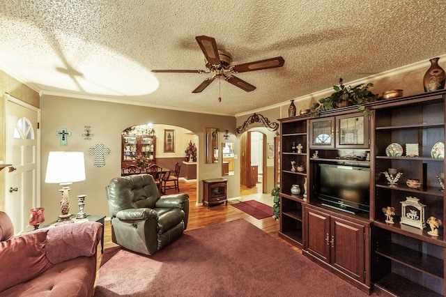 living room featuring crown molding, ceiling fan, hardwood / wood-style flooring, and a textured ceiling