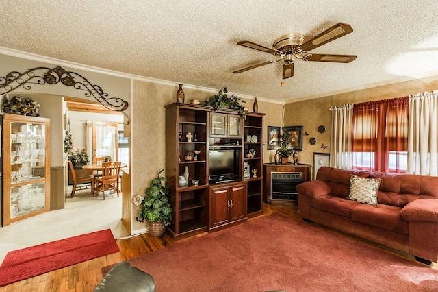 living room with crown molding, ceiling fan, wood-type flooring, and a textured ceiling