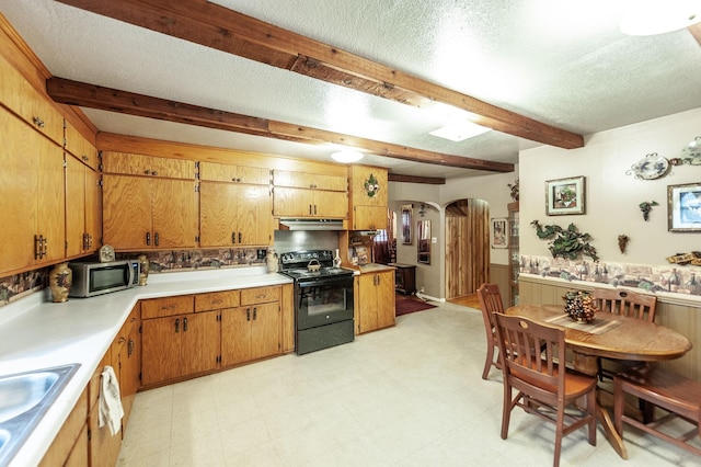 kitchen with wood walls, beamed ceiling, sink, black range with electric stovetop, and a textured ceiling