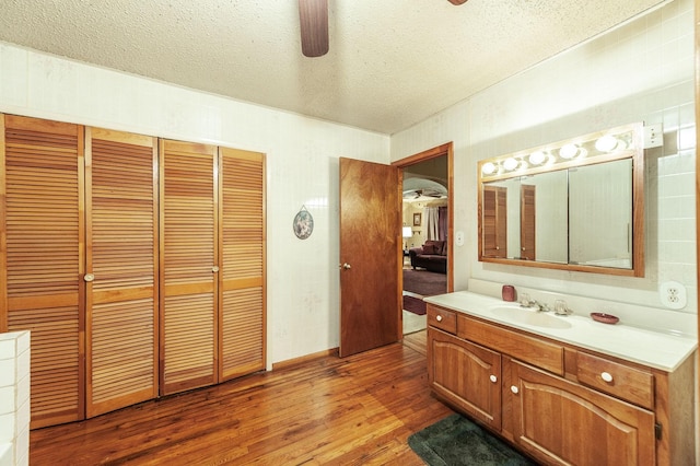 bathroom with ceiling fan, vanity, hardwood / wood-style floors, and a textured ceiling