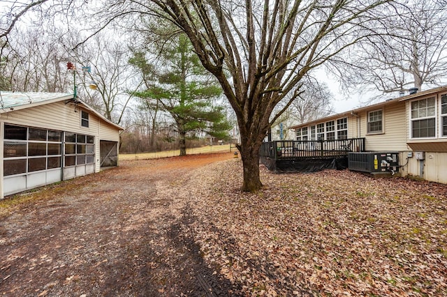 view of yard featuring a garage, a wooden deck, and cooling unit