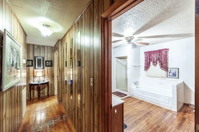 hallway featuring wood-type flooring, a textured ceiling, and wood walls