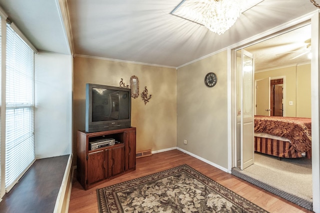 living room with crown molding, wood-type flooring, and ceiling fan with notable chandelier