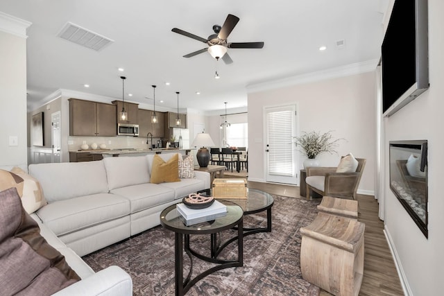 living room with ornamental molding, dark wood finished floors, visible vents, and recessed lighting