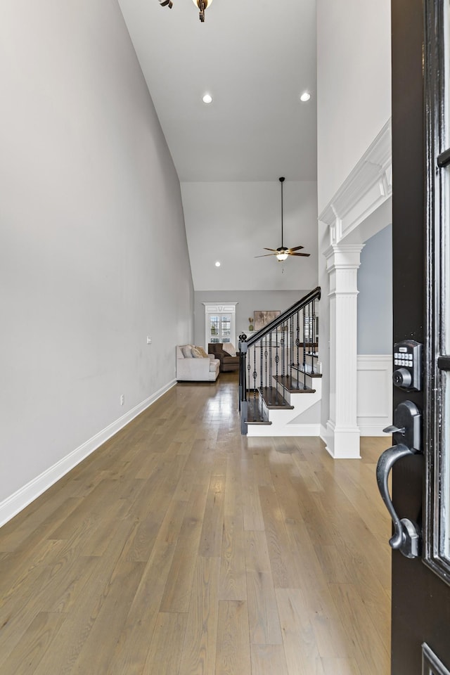 living room featuring high vaulted ceiling, light hardwood / wood-style floors, ceiling fan, and ornate columns