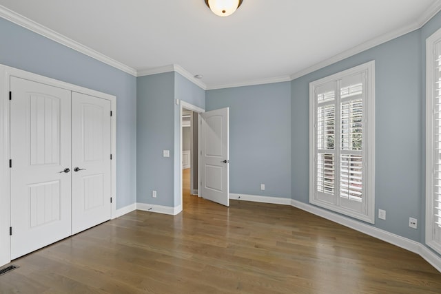 unfurnished bedroom with hardwood / wood-style flooring, crown molding, and a closet