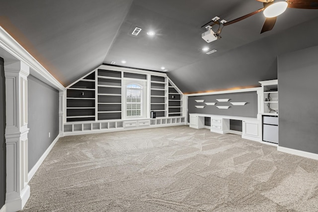 bonus room featuring vaulted ceiling, built in desk, light colored carpet, ceiling fan, and built in shelves