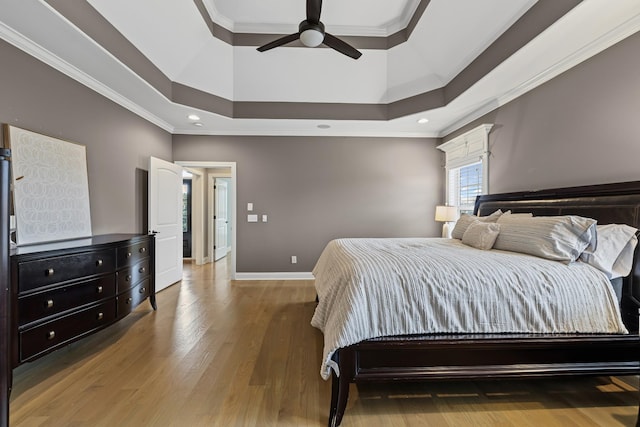 bedroom with wood-type flooring, a high ceiling, ceiling fan, a raised ceiling, and crown molding