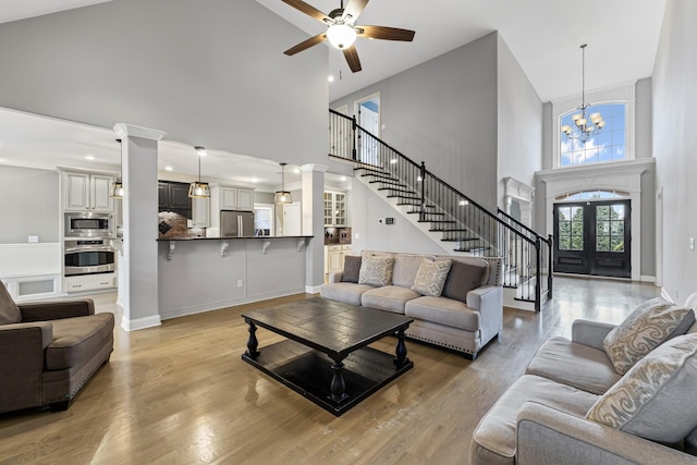 living room with an inviting chandelier, hardwood / wood-style flooring, french doors, and a towering ceiling