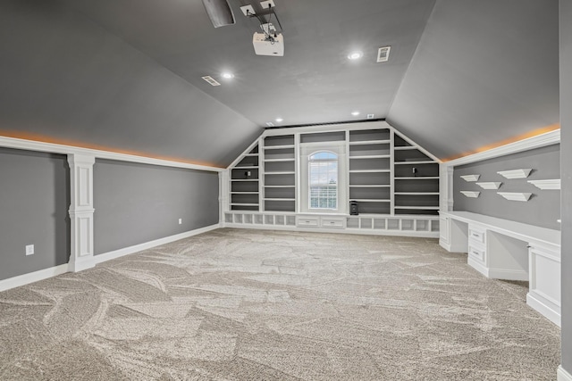 bonus room with lofted ceiling, light colored carpet, built in desk, and built in features