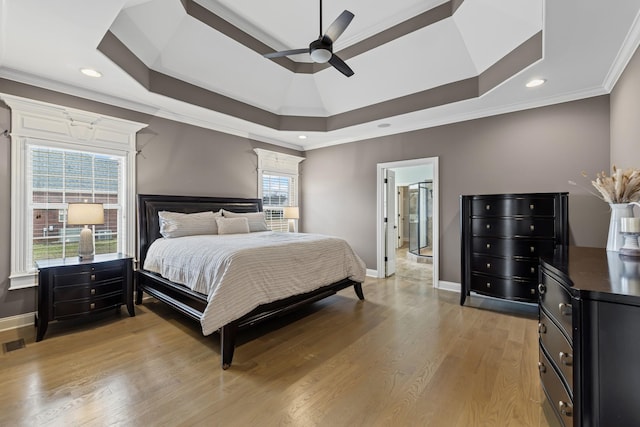 bedroom with crown molding, ceiling fan, light wood-type flooring, and a tray ceiling