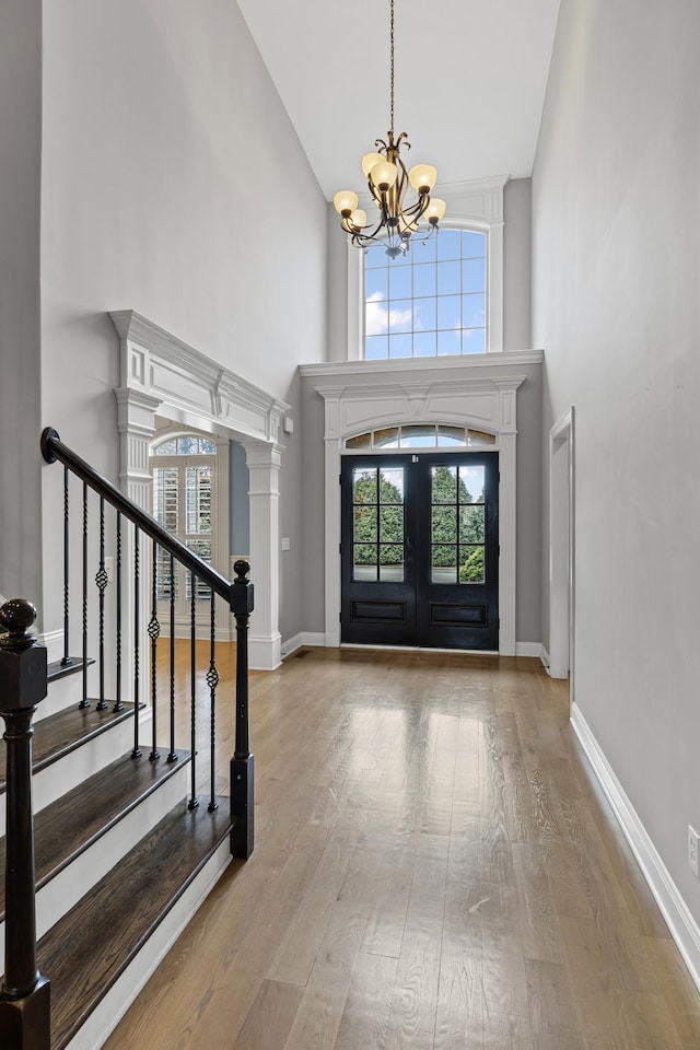 foyer with french doors, a chandelier, a high ceiling, and light wood-type flooring