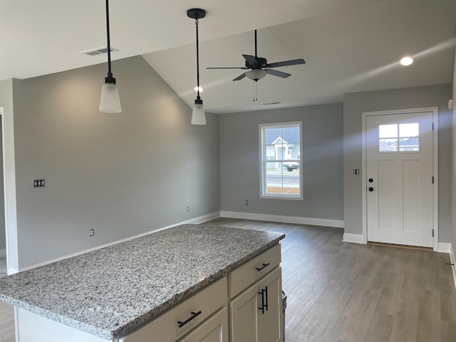 interior space with a healthy amount of sunlight, white cabinets, light stone counters, and light hardwood / wood-style flooring