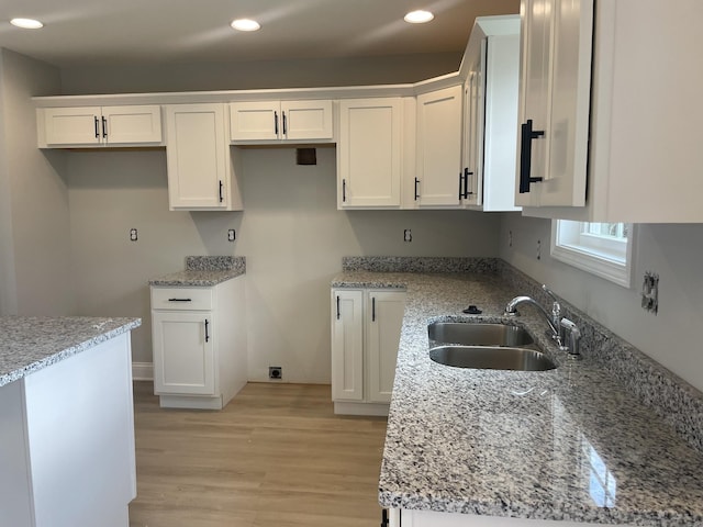 kitchen featuring white cabinetry, sink, and light stone counters