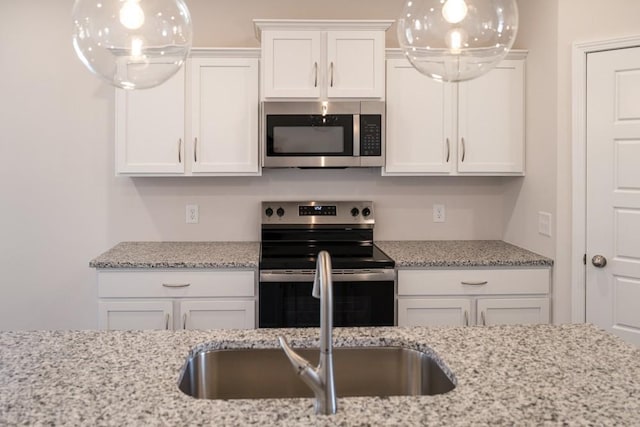 kitchen with white cabinetry, stainless steel appliances, sink, and light stone counters