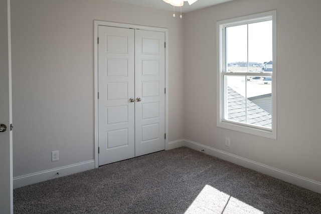 unfurnished bedroom with dark carpet and a closet