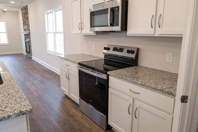 kitchen featuring white cabinetry, a healthy amount of sunlight, appliances with stainless steel finishes, and light stone countertops