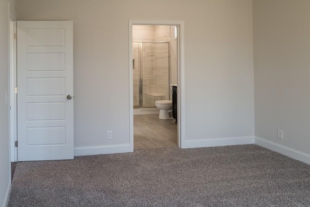 unfurnished bedroom featuring ensuite bathroom and carpet flooring