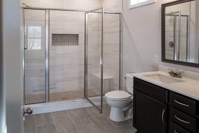 bathroom featuring a shower with door, vanity, and toilet