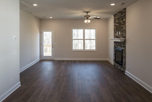 unfurnished living room with dark hardwood / wood-style flooring, a stone fireplace, and ceiling fan